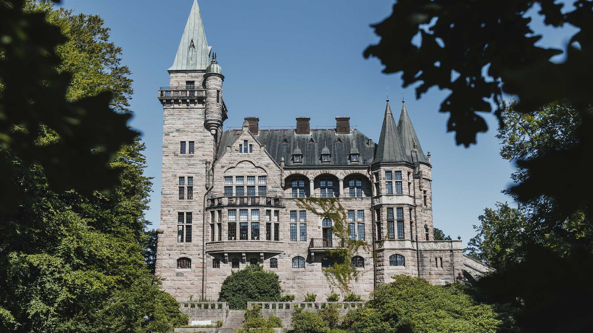 Teleborgs Slott sett genom lövverk en sommardag